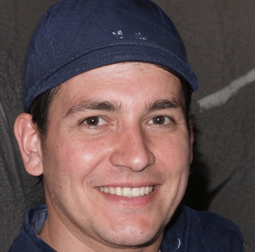 Homme souriant portant une casquette bleue.